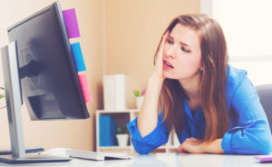 Stressed young woman sitting at her desk in front of the computer
