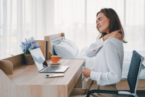 Women with neck pain at desk - needing better workplace ergonomics