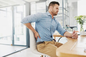 Sitting health risks, man with back pain at desk